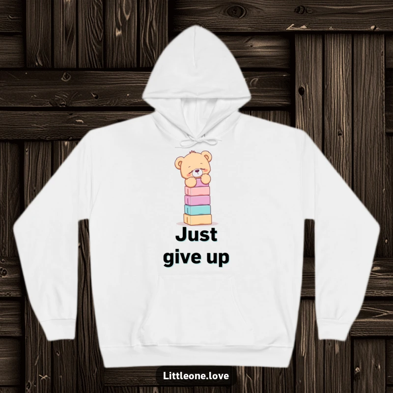 Funny hoodie with a drowsy teddy bear attempting to balance an impossibly tall stack of colorful blocks, a cozy and humorous design.