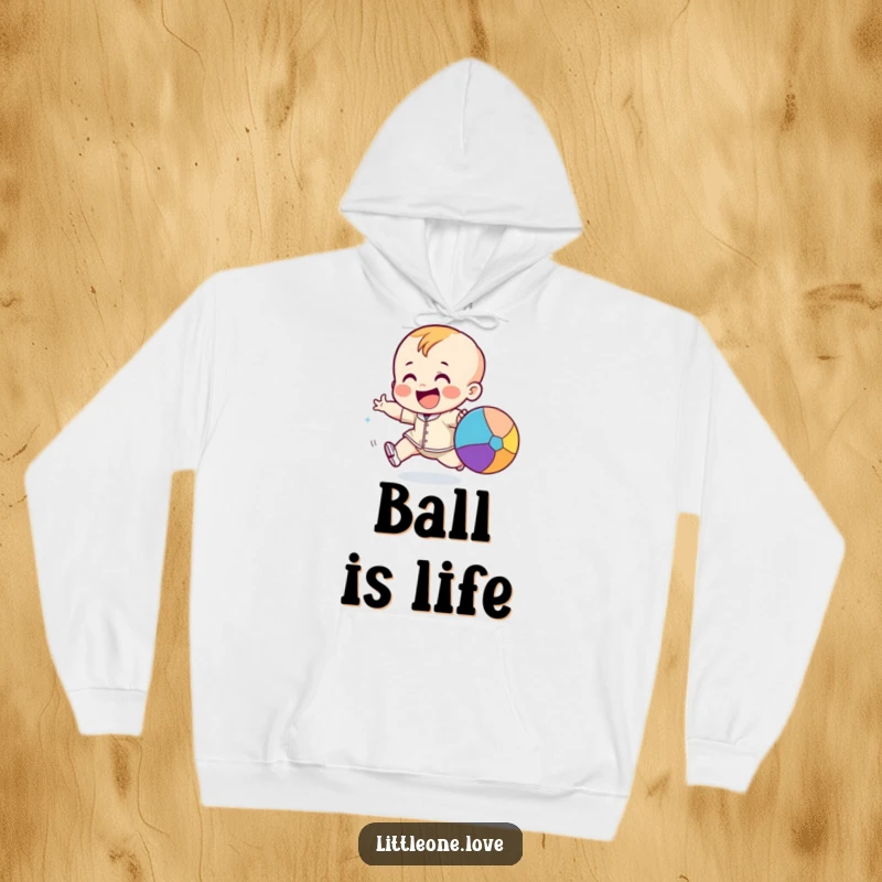 Funny giggling toddler character excitedly chasing a bouncing colorful ball, featured on a warm and comfortable hoodie.
