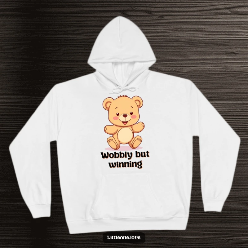 Funny hoodie with a happy teddy bear character learning to take wobbly steps, offering cozy comfort and a symbol of adorable, determined progress, ideal funny gift.